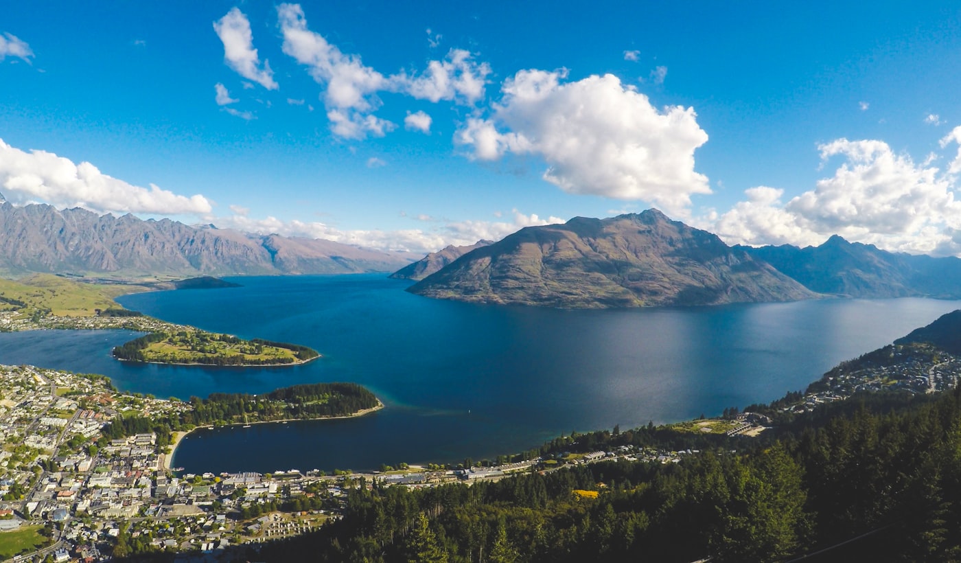 Aerial view of Queenstown, Lake Wakatipu and The Remarkables under a blue sky